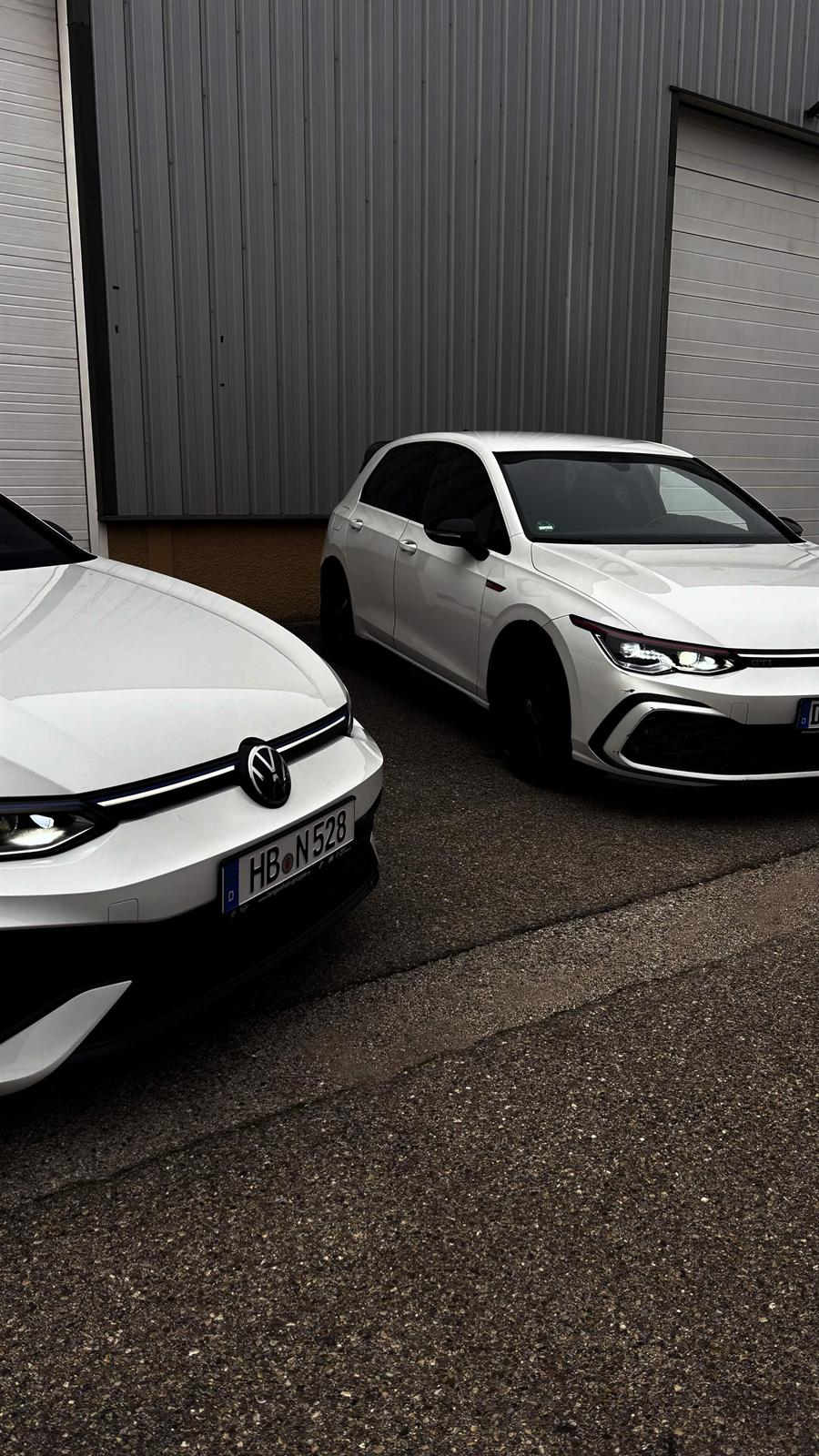 Volkswagen Golf 8 R et Golf 8 GTI blanches garées devant un hangar